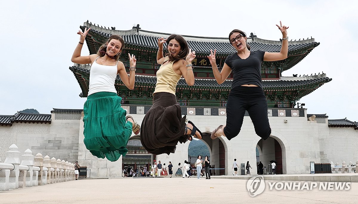 Spanish tourists jump in the air for a photo in front of Gwanghwamun in central Seoul on Aug. 30, 2026. (Yonhap) (END)