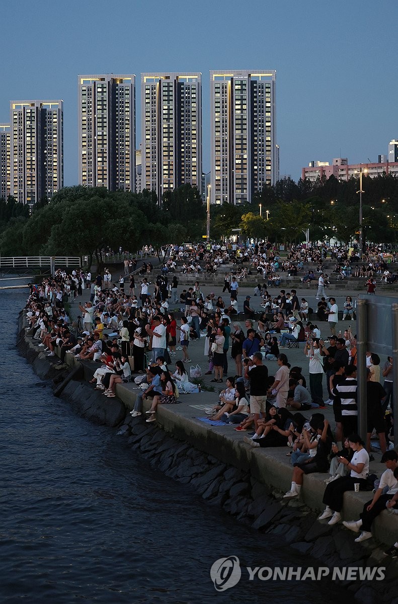 People gather at a riverside park in Seoul's Banpo district as a citywide tropical night advisory is issued across Seoul on Aug. 2, 2026. (Yonhap) (END)