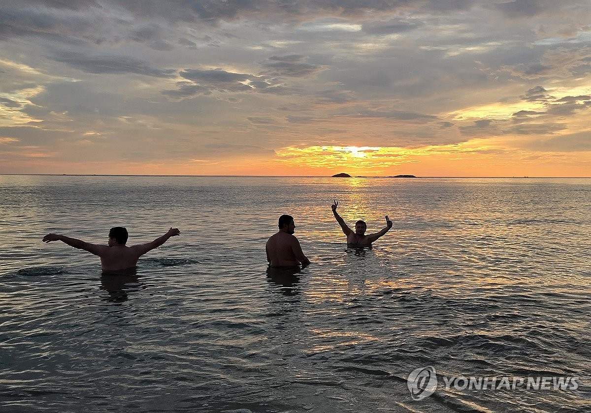 Tourists from abroad play in the water to cool off at Gyeongpo Beach in Gangneung, Gangwon Province, on South Korea's east coast, in the early hours of Aug. 25, 2026, after going through a tropical night, when the thermometer does not dip below 25 C. (Yonhap) (END)