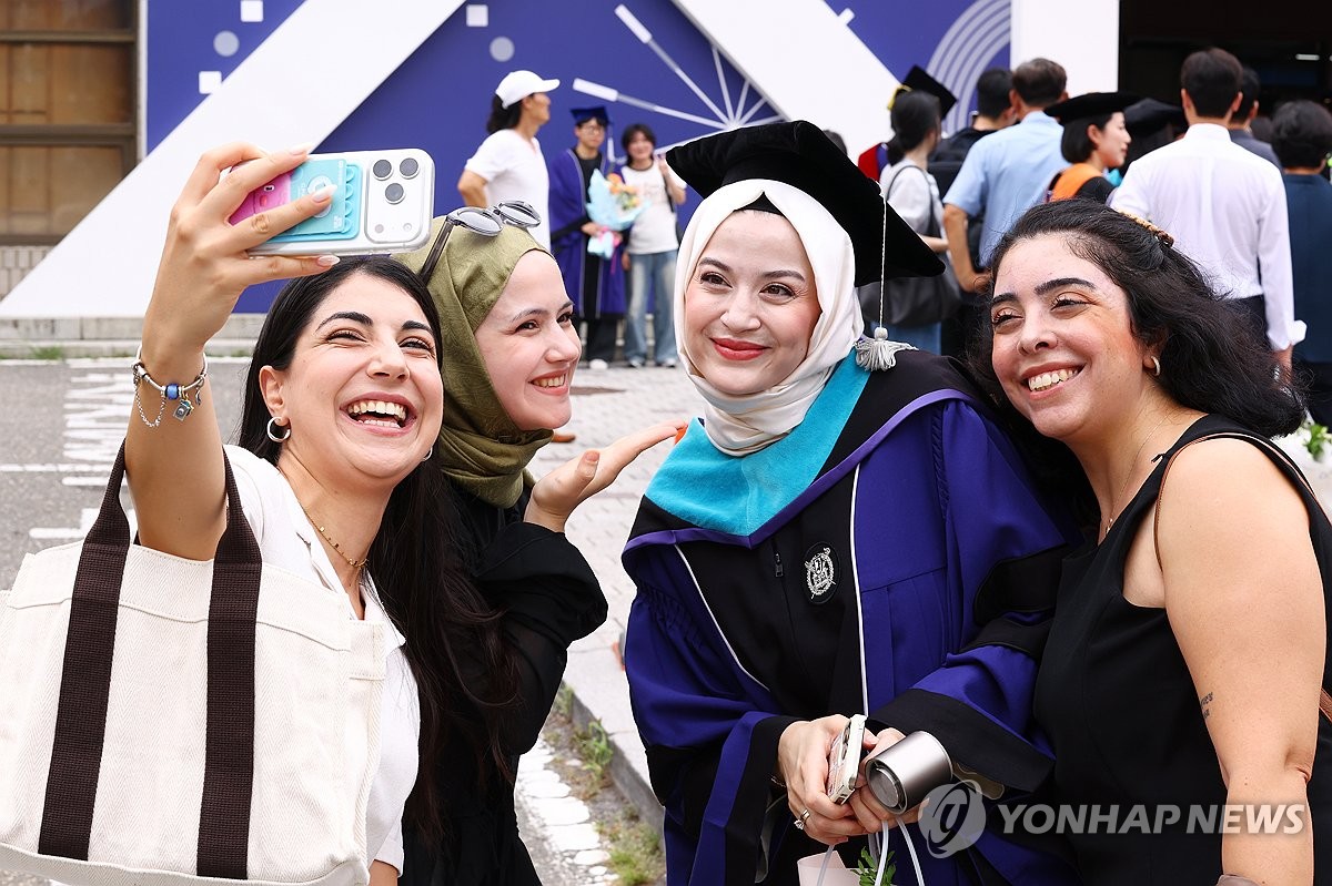 A graduate takes a photo with her friends at Seoul National University in Seoul on Aug. 28, 2026, as part of a graduation ceremony. (Yonhap) (END)