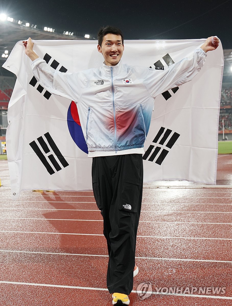 Woo Sang-hyeok of South Korea holds the South Korean flag after winning the bronze medal in the men's high jump final at the Aichi-Nagoya Asian Games at Nagoya City Mizuho Park Athletic Stadium in Nagoya, central Japan, on Sept. 27, 2026. (Yonhap) (END)
