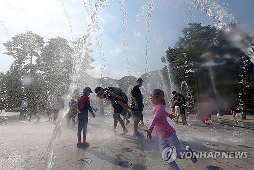 Children and their parents cool off at a water fountain in the southeastern city of Yangsan on Aug. 2, 2026, when the temperature soared to a national record of 42.5 C. (Yonhap)
