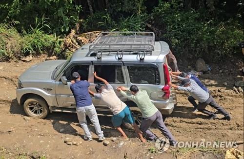 Members of the second contingent of South Korea's Korea Disaster Relief Team (KDRT) push a vehicle stuck in mud while traveling to a village in Nepal on Sept. 14, 2026. (Yonhap)