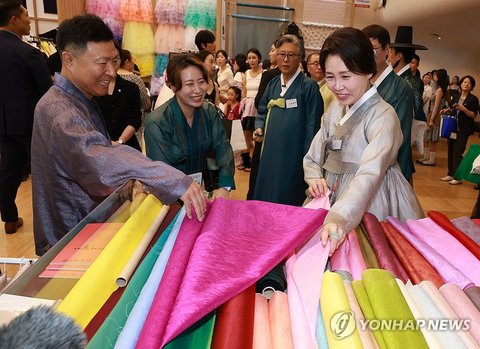 Kim Hea Kyung (R), wife of President Lee Jae Myung, looks at fabric used to make "hanbok," traditional Korean attire, during Hanbok Expo, an industry fair on the Korean dress, in Seoul on Aug. 14, 2026. (Yonhap) (END)