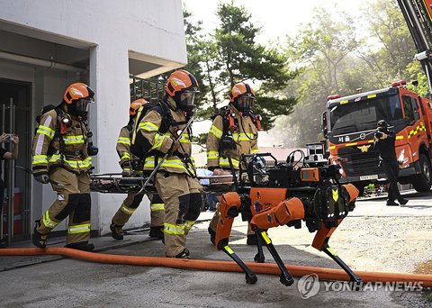 Firefighters carry a simulated victim alongside a firefighting robot as they take part in a drill to contain a fire at a fire service academy in Seoul on Aug. 5, 2026, as part of this year's meeting on integrated defense by the Seoul metropolitan government. (Pool photo) (Yonhap) (END)