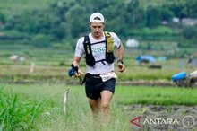  A participant runs past rice fields during a trail running competition. 