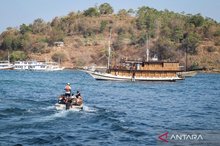 Tourists sail on a boat to board a traditional pinisi ship bound for Komodo National Park in Labuan Bajo