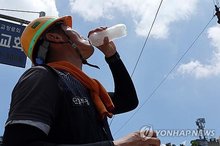 A construction worker drinks water while working outdoors in the South Korean western city of Gwangju on July 2, 2025. (Yonhap)