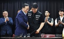 Choi Seung-ho (R, front), head of Samsung Electronics Co.'s largest labor union, shakes hands with Yeo Myeong-gu (L, front), head of Samsung Electronics Co.'s device solutions division's people team, after signing a tentative agreement in Suwon, south of Seoul, on May 20, 2026. (Pool photo) (Yonhap)