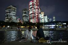 People cool off at Mulbit Square along the Han River on Aug. 20, 2024, during the 30th consecutive tropical night, setting a new record in the capital. (Yonhap)