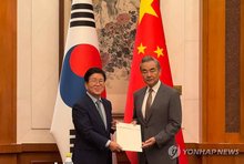 Former National Assembly Speaker Park Byeong-seug (L) delivers President Lee Jae Myung's personal letter for Chinese President Xi Jinping during his meeting with Chinese Foreign Minister Wang Yi in Beijing on Aug. 24, 2025. (Pool photo) (Yonhap)