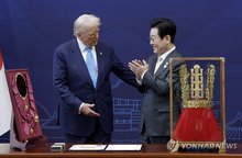 President Lee Jae Myung (R) claps as he presents U.S. President Donald Trump a replica of the Cheonmachong crown and the Grand Order of Mugunghwa -- the country's highest decoration -- during a welcoming ceremony for the U.S. president at the Gyeongju National Museum in the southeastern city of Gyeongju on Oct. 29, 2025. (Pool photo) (Yonhap)