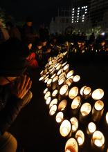 People pray as they observe a moment of silence in Kobe in the early morning of Jan. 17, 2025, the 30th anniversary of the magnitude 7.3 earthquake that killed 6,434 people. (Kyodo)