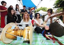 Foreign students try out "pungmullori," a traditional Korean art form that combines music, dance and acrobatics, during a club expo of Ajou University held on the school's campus in Suwon, Gyeonggi Province, in this file photo from Sept. 2, 2026. (Yonhap)
