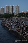 People gather at a riverside park in Seoul's Banpo district as a citywide tropical night advisory is issued across Seoul on Aug. 2, 2026. (Yonhap) (END)