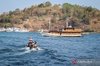 Tourists sail on a boat to board a traditional pinisi ship bound for Komodo National Park in Labuan Bajo